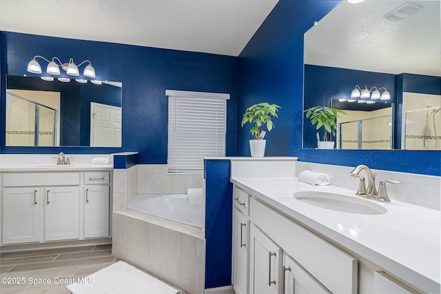 bathroom featuring vanity, separate shower and tub, and a textured ceiling