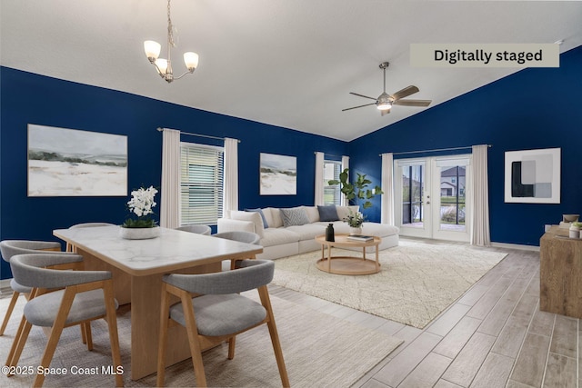 living room featuring vaulted ceiling, ceiling fan with notable chandelier, and light hardwood / wood-style flooring