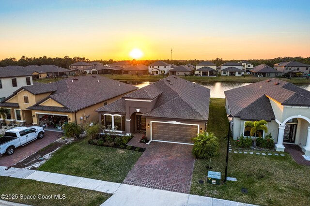 view of front of home featuring a garage, a water view, and a lawn