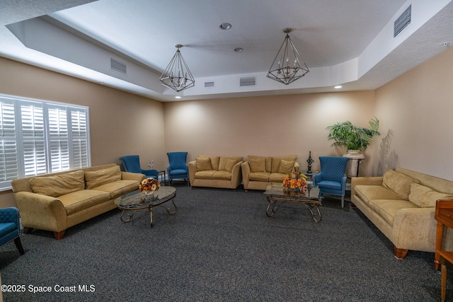 carpeted living room with a raised ceiling and an inviting chandelier