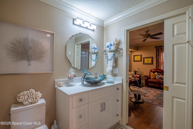 bathroom with hardwood / wood-style floors, vanity, toilet, ornamental molding, and a textured ceiling