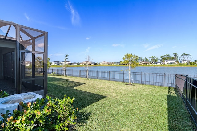 view of yard with glass enclosure, cooling unit, and a water view