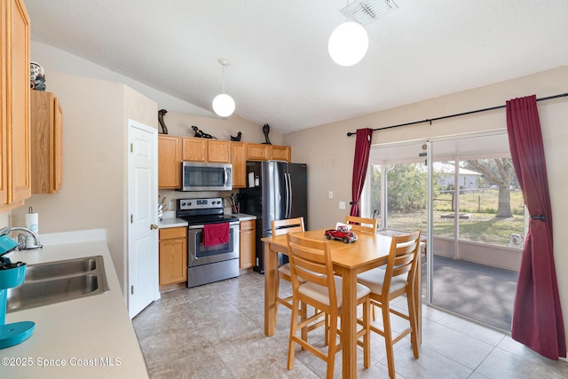 kitchen with appliances with stainless steel finishes, a textured ceiling, vaulted ceiling, sink, and pendant lighting