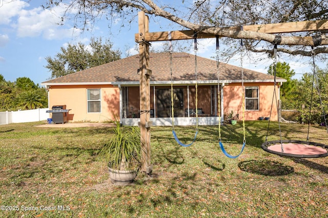 back of property with a yard, a trampoline, and a sunroom