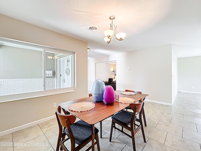 dining room featuring a textured ceiling, light tile patterned flooring, baseboards, visible vents, and a chandelier
