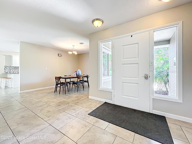 foyer featuring a chandelier, a textured ceiling, a healthy amount of sunlight, and light tile patterned floors