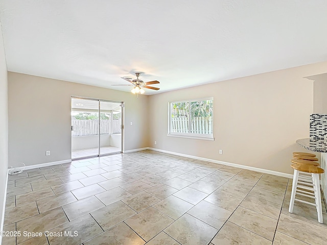 empty room with baseboards, a ceiling fan, and light tile patterned floors