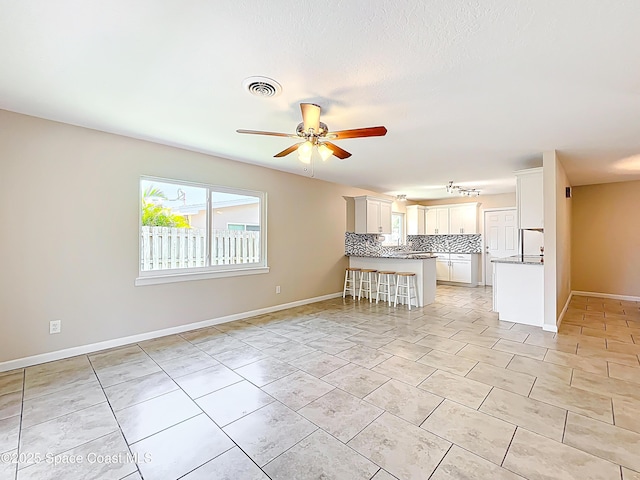 kitchen featuring backsplash, visible vents, a peninsula, open floor plan, and ceiling fan