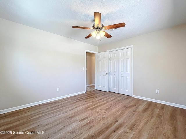unfurnished bedroom with wood finished floors, a closet, a ceiling fan, and baseboards