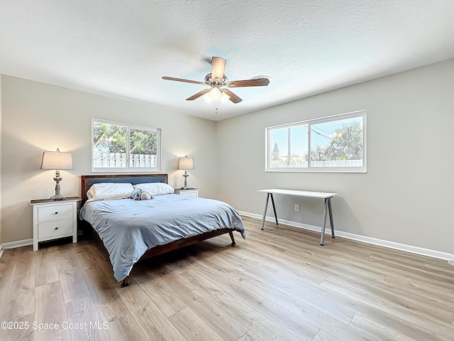 bedroom with a textured ceiling, light wood finished floors, and baseboards