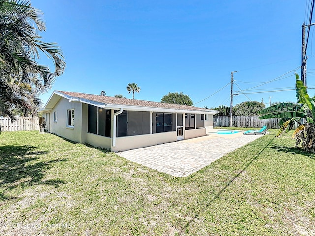 back of house with a fenced backyard, stucco siding, a patio area, a lawn, and a sunroom