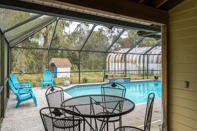 view of pool with a patio area, glass enclosure, and a storage shed