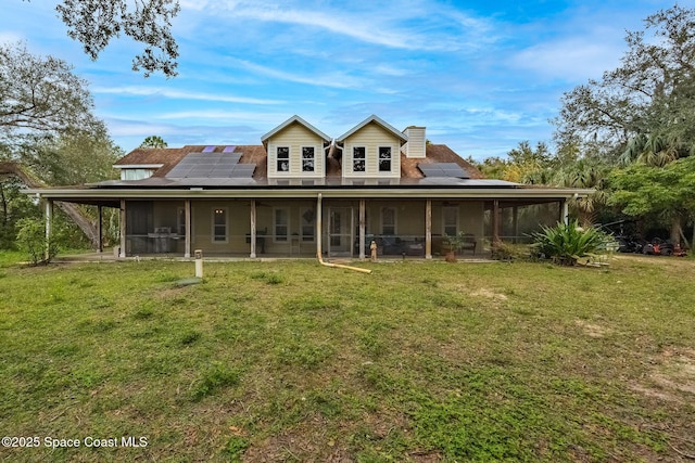 rear view of house with solar panels, a yard, and a sunroom