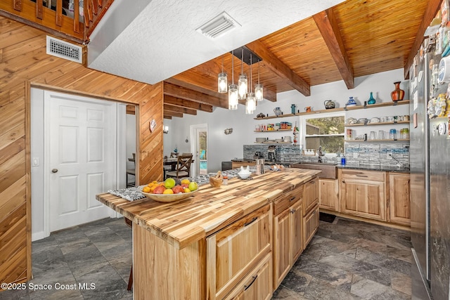 kitchen featuring decorative light fixtures, wooden walls, beamed ceiling, wood counters, and wooden ceiling