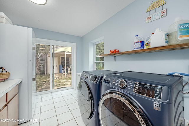 laundry area with washer and dryer, light tile patterned flooring, and cabinets