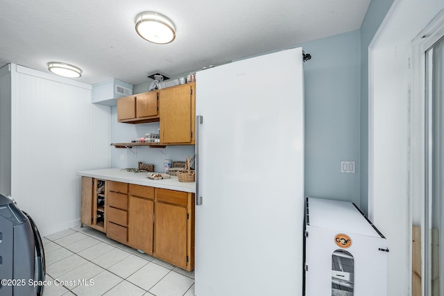 kitchen with washer / dryer, a textured ceiling, and light tile patterned floors