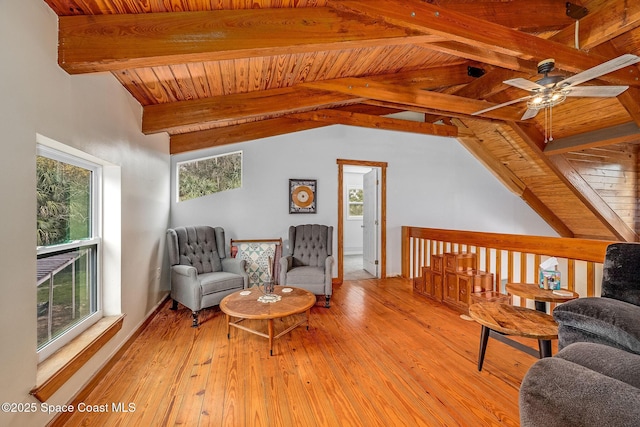 living area with ceiling fan, light hardwood / wood-style floors, lofted ceiling with beams, and plenty of natural light