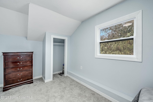 unfurnished bedroom with light carpet, a closet, and lofted ceiling