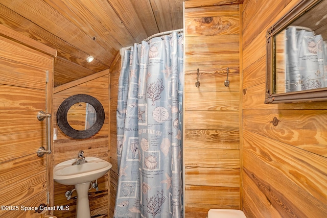 bathroom featuring sink, wood ceiling, and wooden walls