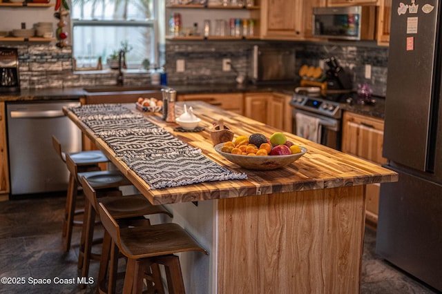 kitchen featuring a breakfast bar, stainless steel appliances, butcher block countertops, and sink