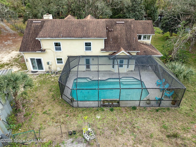 view of pool featuring a lawn, glass enclosure, and a patio area