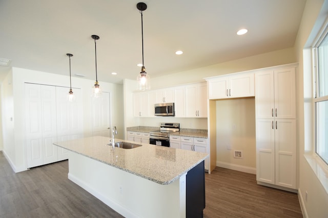 kitchen with a kitchen island with sink, sink, light stone counters, white cabinetry, and stainless steel appliances