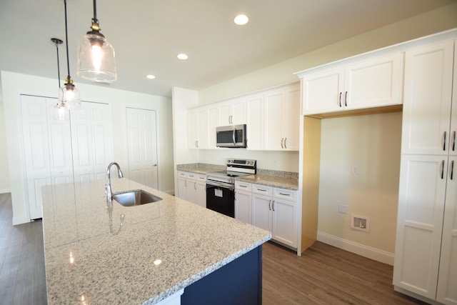 kitchen featuring stainless steel appliances, a kitchen island with sink, sink, white cabinets, and hanging light fixtures