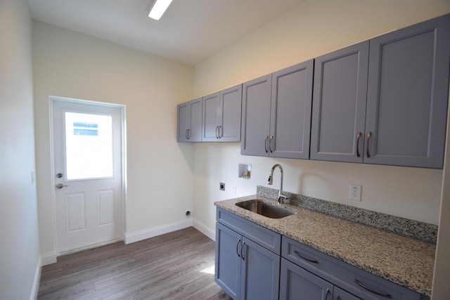 kitchen with light wood-type flooring, gray cabinets, dark stone counters, and sink