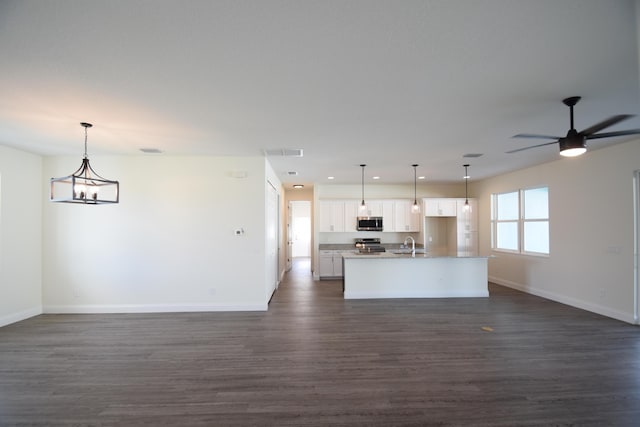 kitchen with appliances with stainless steel finishes, sink, white cabinetry, hanging light fixtures, and an island with sink