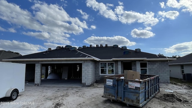 rear view of property featuring a garage and central air condition unit