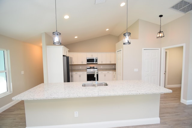 kitchen featuring white cabinets, appliances with stainless steel finishes, and an island with sink