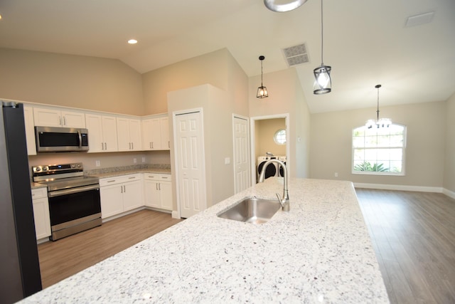 kitchen featuring sink, separate washer and dryer, light stone counters, white cabinets, and appliances with stainless steel finishes