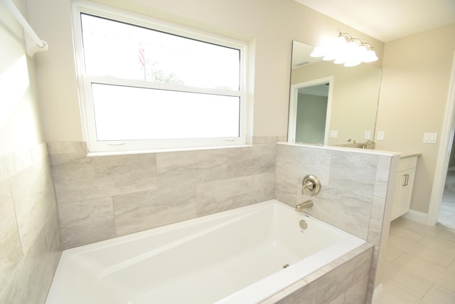 bathroom with tile patterned flooring, vanity, and tiled bath