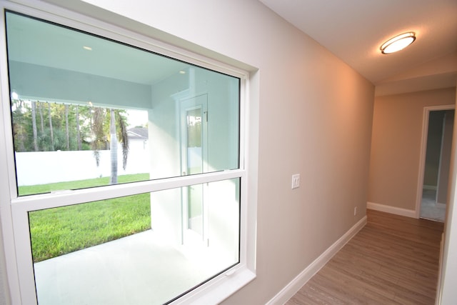 hall with hardwood / wood-style floors and vaulted ceiling