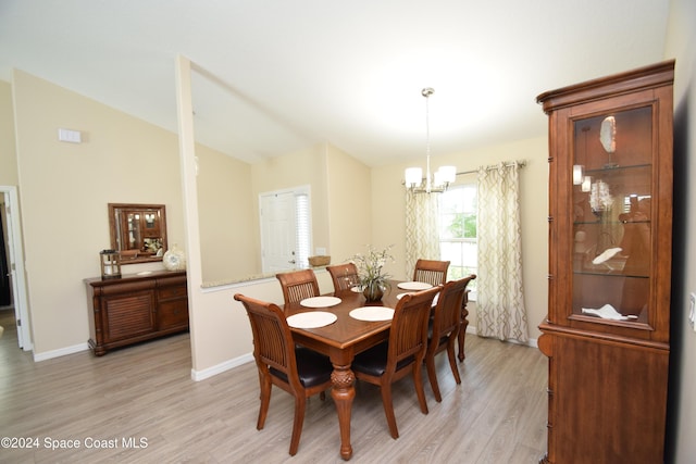 dining space with light hardwood / wood-style floors, vaulted ceiling, and a chandelier