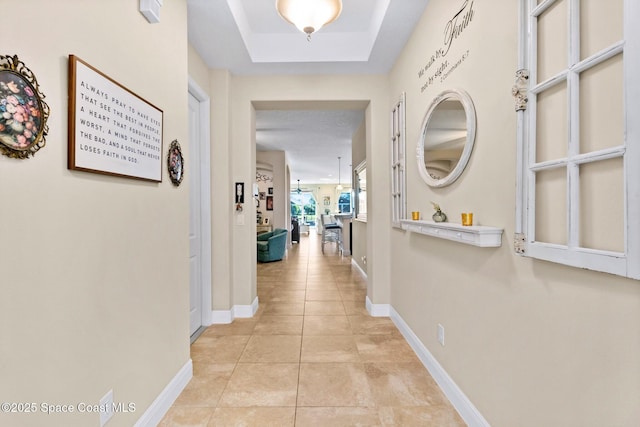 hallway featuring a raised ceiling and light tile patterned floors