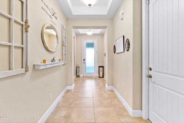 hallway featuring a raised ceiling and light tile patterned floors