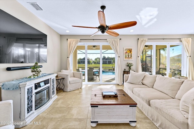 tiled living room with ceiling fan and a textured ceiling