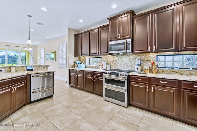 kitchen featuring decorative backsplash, dark brown cabinets, stainless steel appliances, and hanging light fixtures