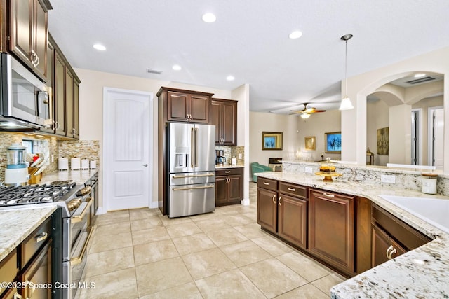 kitchen featuring pendant lighting, ceiling fan, decorative backsplash, light tile patterned floors, and stainless steel appliances