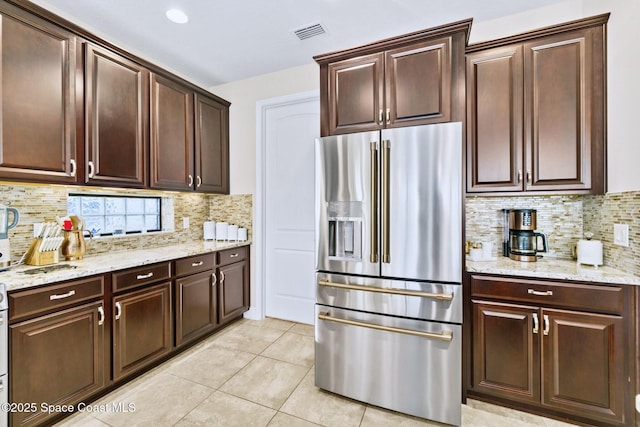 kitchen featuring backsplash, stainless steel fridge with ice dispenser, light tile patterned floors, and light stone counters