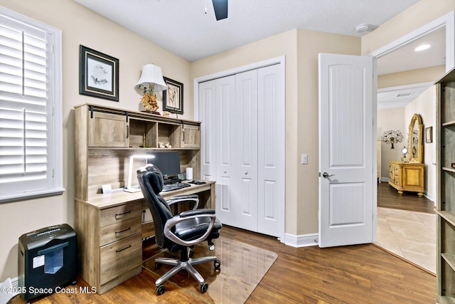 office area featuring a healthy amount of sunlight, ceiling fan, and dark wood-type flooring