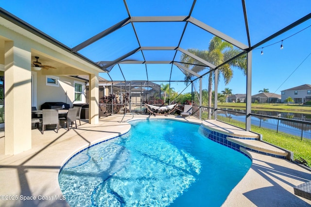 view of swimming pool with glass enclosure, ceiling fan, a water view, and a patio