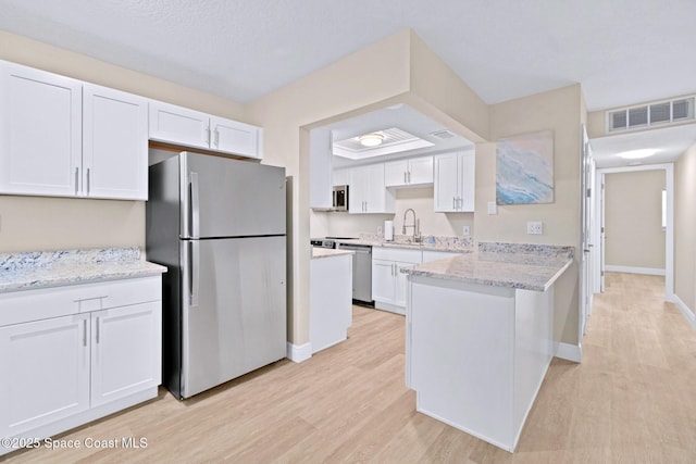 230 Columbia Dr Unit 113, Cape Canaveral, FL 32920 - kitchen with appliances with stainless steel finishes, light wood finished floors, white cabinets, and a peninsula