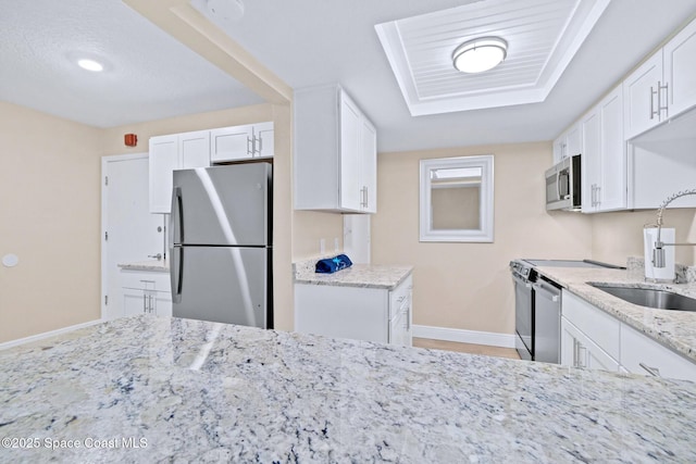 kitchen featuring white cabinetry, sink, stainless steel appliances, light stone counters, and a textured ceiling