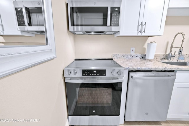 kitchen featuring white cabinets, light stone counters, sink, and stainless steel appliances