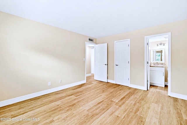 unfurnished bedroom with connected bathroom, light hardwood / wood-style flooring, and sink