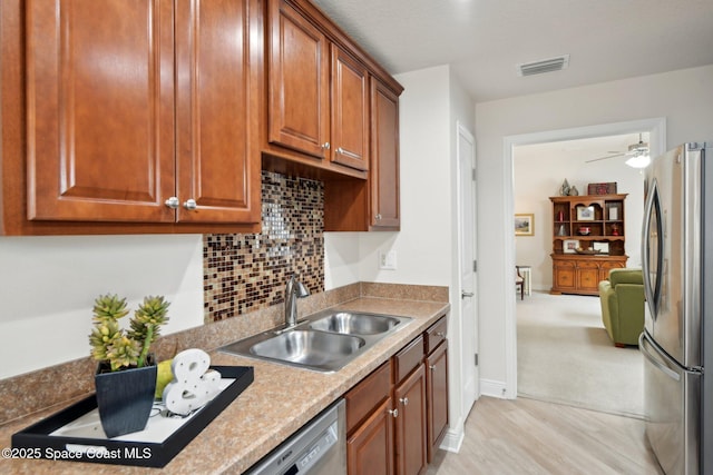 kitchen featuring sink, tasteful backsplash, light wood-type flooring, ceiling fan, and stainless steel appliances