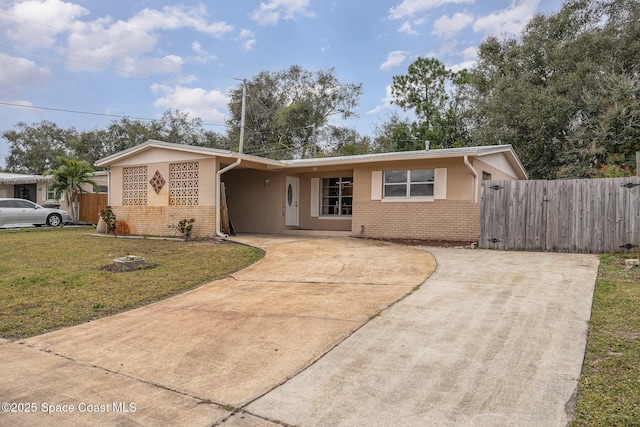 ranch-style house with a front yard, concrete driveway, fence, and brick siding