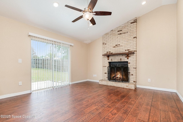 unfurnished living room featuring a brick fireplace, dark hardwood / wood-style floors, ceiling fan, and vaulted ceiling